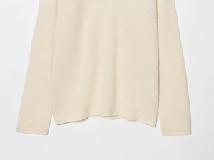 Detailed macro view of the cream wool blend knit sweater with elastic hem and lace texture
