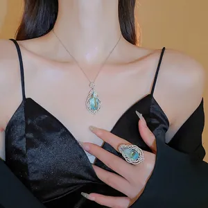 Elegant jewelry set featuring a pear-cut blue gemstone pendant and matching ring