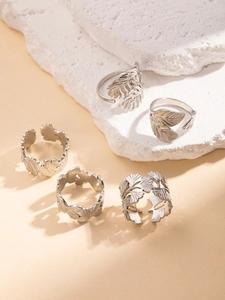 Detailed view of five silver-toned botanical rings featuring leaf and feather textures
