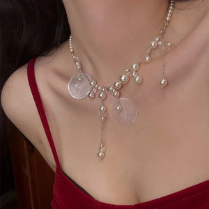 Detail of pearl tassel necklace with silver chain and shell sequins on elegant neckline