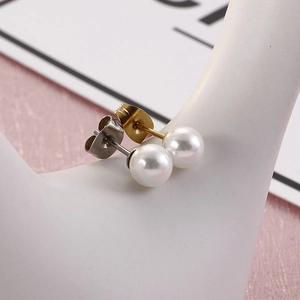 Detailed close-up of pearl earrings showing gold and silver metal backings on a stand