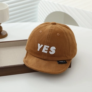 Detail of baby short brim baseball cap with YES embroidery on warm brown cotton