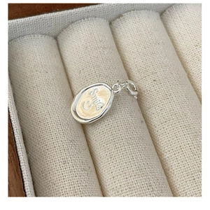Macro shot of silver oval pendant featuring a beige enamel center with Smile engraving