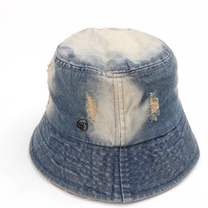 Detailed macro view of distressed denim fabric and metal logo on vintage bucket hat