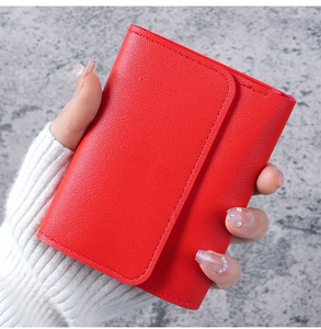 Detailed close-up of a vibrant red lychee grain leather wallet held in hand