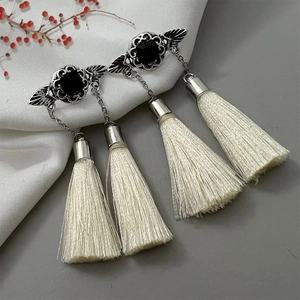 Detail view of vintage silver tassel earrings with black stone on white silk background