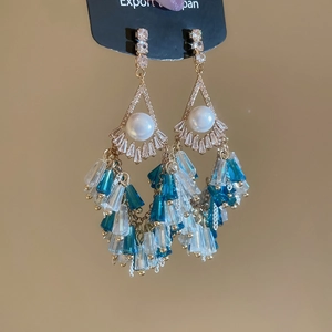 Detailed macro view of vintage gold chandelier earrings with pearls and blue tassels
