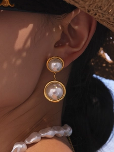 French vintage style gold earrings and baroque pearl necklace worn by a model in soft light
