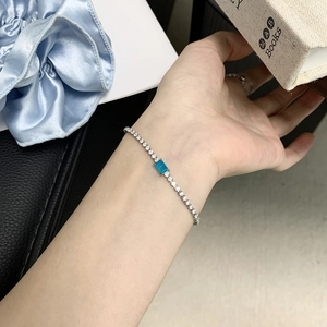 Elegant bracelet with blue rectangular crystal and white zircons worn on female wrist