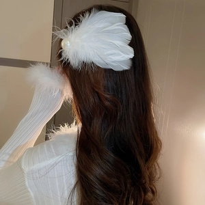Detail of white feather hair clip with pearl embellishment on model's hairstyle