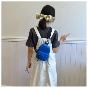 Detail view of blue nylon mini crossbody bag worn by model showing compact sporty design