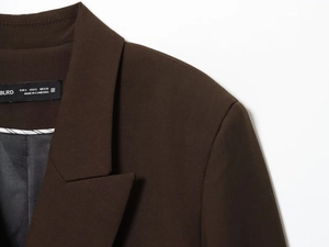 Detail of shoulder seams and fabric texture on a dark brown double-breasted blazer