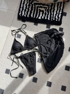 Close-up of black 3-piece bikini set featuring textured rippled fabric and matching sarong