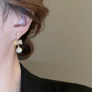 Boucles d'oreilles nœud élégantes avec zircon et perle portées par un mannequin en détail