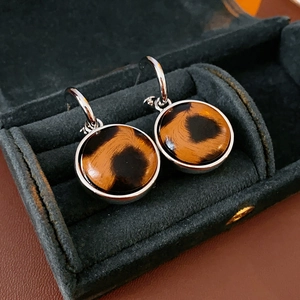 Close-up of leopard print hoop earrings presented in a green velvet jewelry case