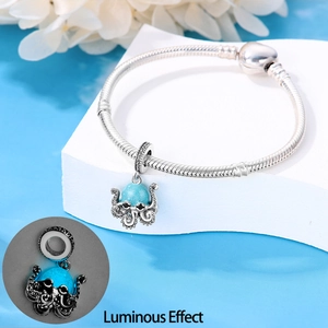 Detail showing luminous blue octopus charm on a silver snake chain bracelet