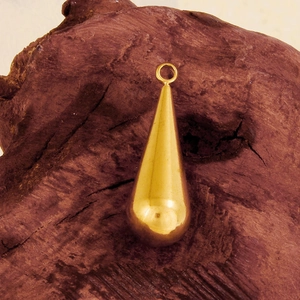 Detailed view of a polished golden teardrop pendant on a textured dark wood background
