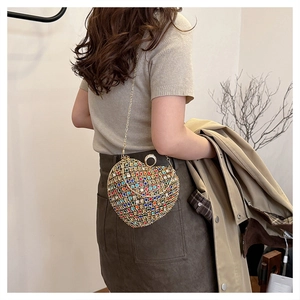 Model wearing a colorful rhinestone heart-shaped evening bag with a gold chain strap