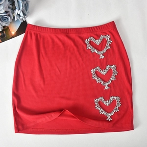 Detail of red ribbed knit mini skirt featuring three sparkling rhinestone heart patches