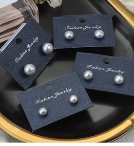 Close-up of four pairs of grey freshwater pearl earrings in various sizes on navy cards