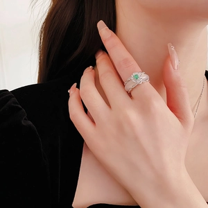 Close-up of a vintage-style flower ring with a green gemstone and zircon details