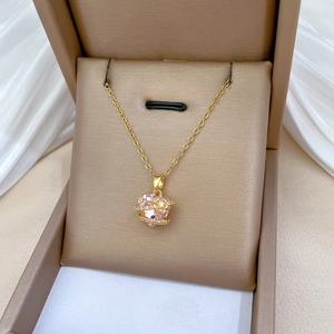 Detail of gold necklace with pink heart crystal pendant and small diamond accents