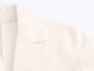 Detail of the high-quality cream wool coat showing collar texture and shoulder stitching