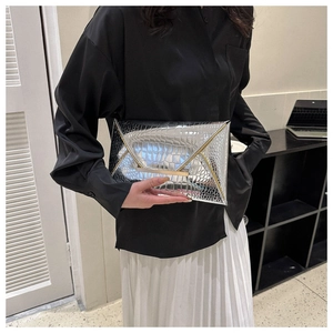 Detailed macro view of a silver envelope clutch with crocodile pattern and metal bar
