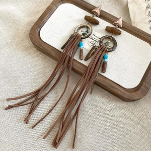 Close-up of Bohemian earrings with dark wood rings and coffee-colored suede tassels
