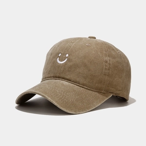 Detailed embroidery of a white smiley face on a brown washed cotton baseball cap