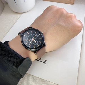 Black quartz watch with brown leather strap and rose gold markers on a person's wrist