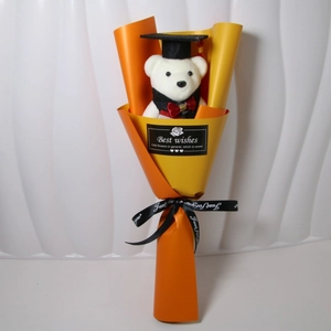 Close-up of a graduation plush bear in black gown with yellow sunflower soap bouquet