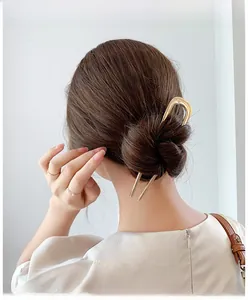 Golden U-shaped metal hairpin styled in a minimalist low bun for elegant hair styling