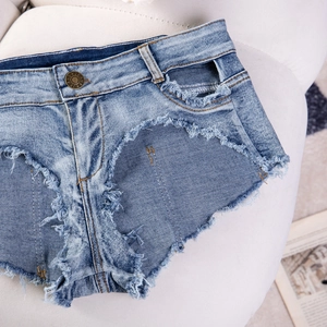Dettaglio di pantaloncini in denim blu a vita alta con orli sfrangiati su pelliccia bianca