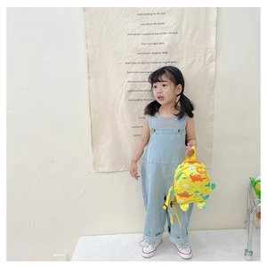 Detail of yellow kids backpack featuring colorful dinosaur prints on adjustable straps