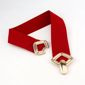 Détail d'une ceinture élastique rouge avec une boucle géométrique en métal doré poli