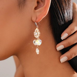Close-up of elegant court style gold earring with opal and heart-shaped crystal on model