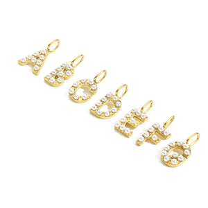 Detailed view of gold alphabet pendants A-G with white pearl inlays for DIY jewelry