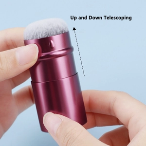 Detail of the retractable makeup brush with maroon casing and soft white bristles