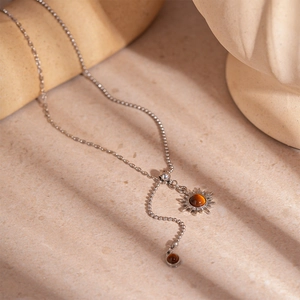 Macro detail of silver sun pendant with tiger eye stone on adjustable mixed chain