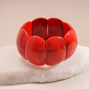 Macro view of wide acrylic bracelet with red marble texture on stone display