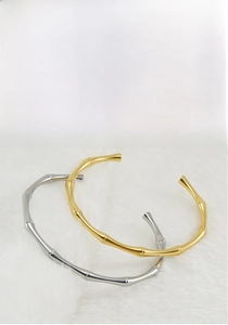 Vista dettagliata di bracciali a forma di bambù in oro e argento con design aperto