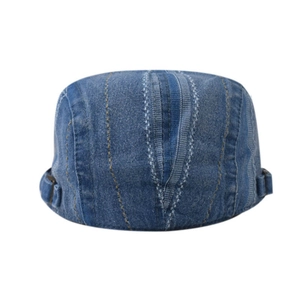 Detail of dark blue denim flat cap showing twill fabric texture and side metal buckle
