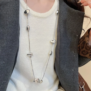Detailed view of long silver Y2K necklace with irregular geometric pebble charms on a model