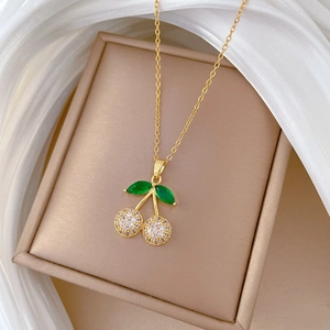Detailed close-up of cherry pendant necklace with green leaf stones and clear zircons