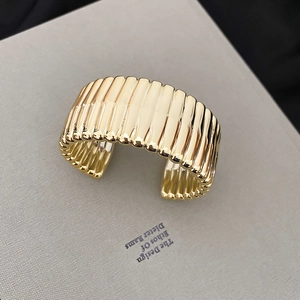Macro detail of the golden fluted cuff bracelet featuring elegant vertical ribbed textures
