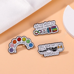 Detailed close-up of three colorful enamel pins with artistic motivational slogans