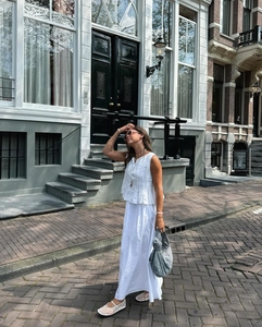 Outdoor shot of white pleated sleeveless tie-front top and matching cotton linen maxi skirt