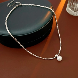 Macro view of silver crushed bead necklace featuring a single white pearl pendant and diamond accent