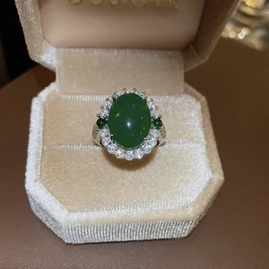 Détail d'une bague halo verte avec zircons dans un écrin à bijoux en velours beige